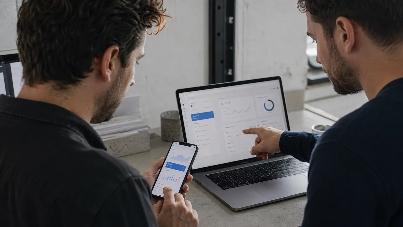 Two professionals testing the same application on a phone and laptop